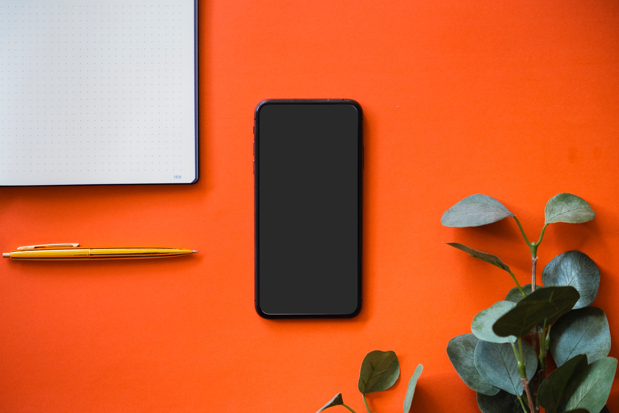 a black smartphone lying on an orange background